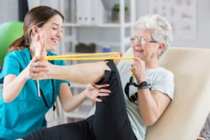 IP Live-in Care at Home uses resistance bands. The woman is stretching out her leg.