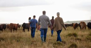 Farmer and family holding hands by cows, representing live-in care for farmers.